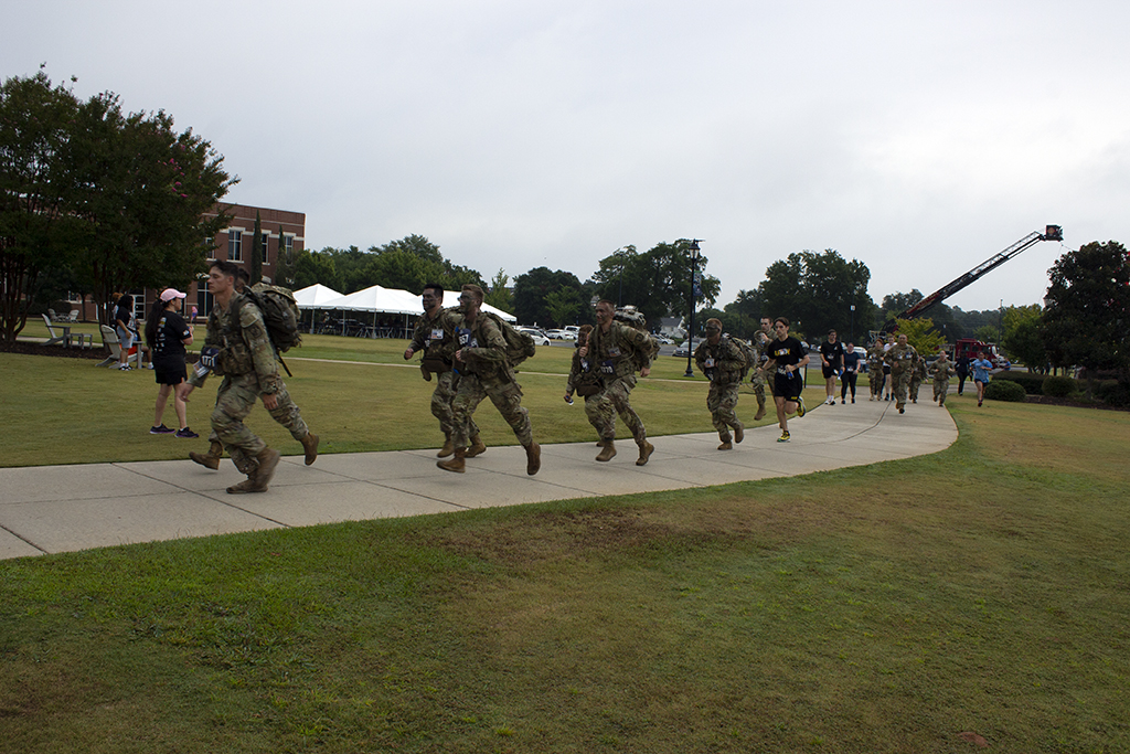 People in uniforms run down the sidewalk.