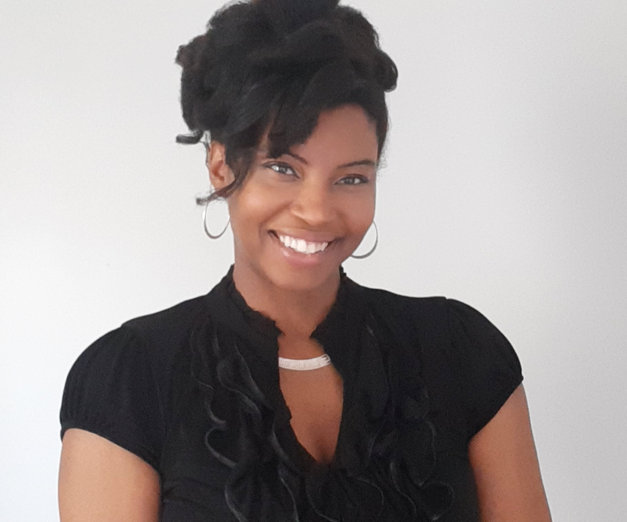 A woman wearing business attire smiles for a photo.