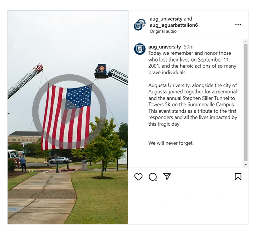 A picture of a large American flag suspended between two firetruck ladders.