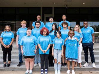 A group of college faculty, staff and students standing in a group outside.