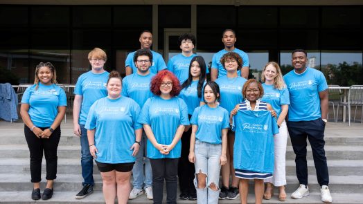 A group of college faculty, staff and students standing in a group outside.