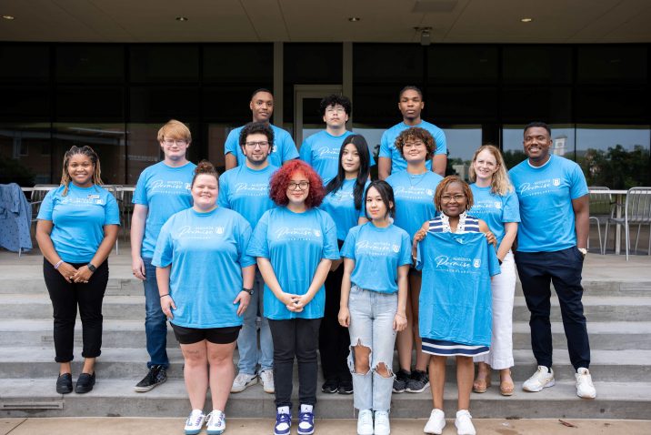 A group of college faculty, staff and students standing in a group outside.