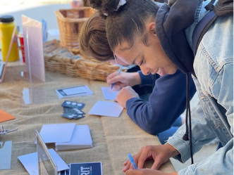 Female student writing a note at a table.