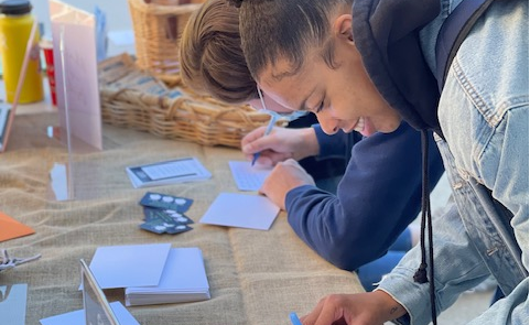 Female student writing a note at a table.