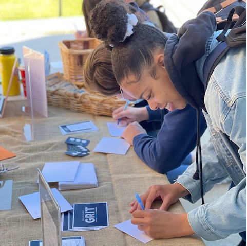 Female student writing a note at a table.