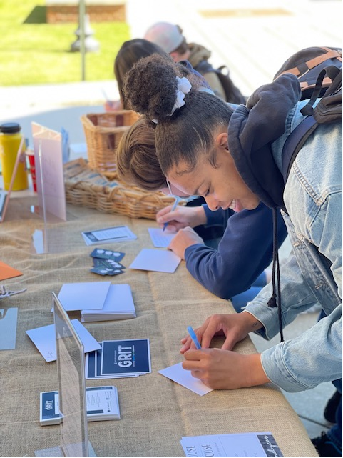 Female student writing a note at a table.