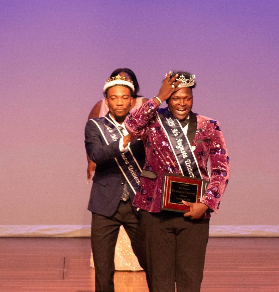 Two crowned male students on stage.