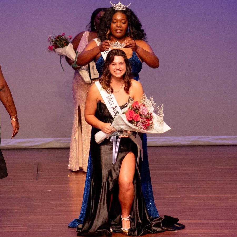 A woman places a crown on another woman's head.