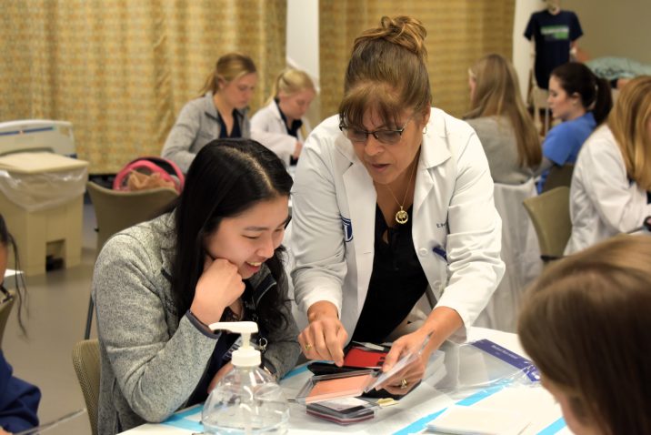 A faculty member shows a student how to properly suture