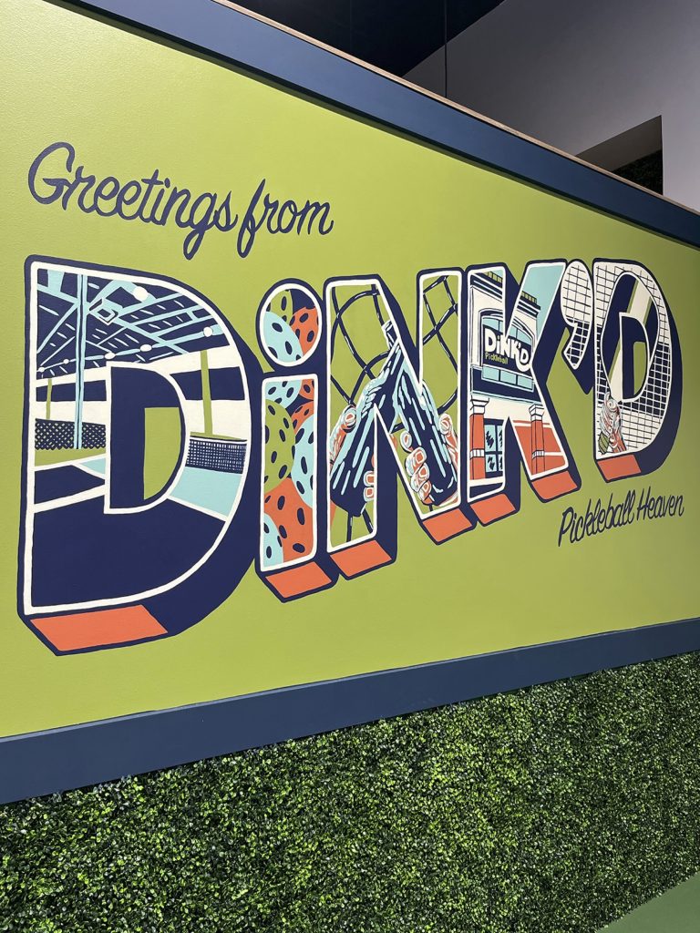 The final version of a mural in a pickleball facility with the words "Greetings from DiNK'D Pickleball Heaven."