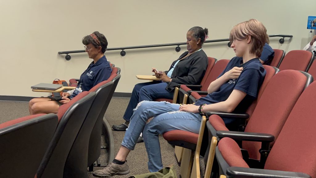 Several women sit facing forward in an auditorium. 