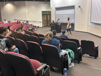 A group of people sitting in an auditorium facing a speaker.