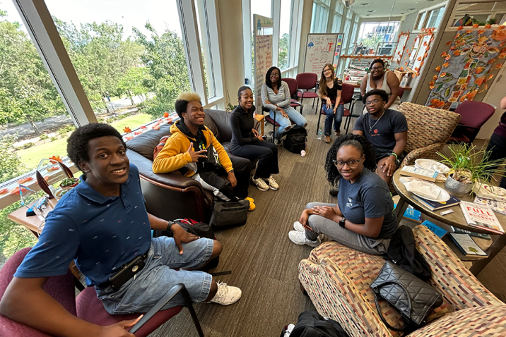 A group of eight college students sit in a circle in an office and talk about issues affecting them.