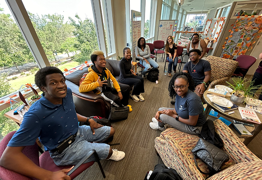 A group of eight college students sit in a circle in an office and talk about issues affecting them.