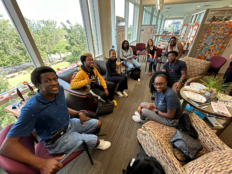 A group of eight college students sit in a circle in an office and talk about issues affecting them.