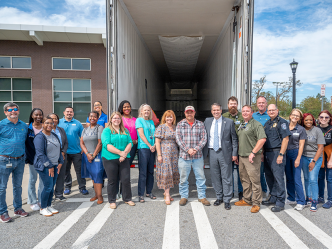 A group of people stand in front of an empty trailer.