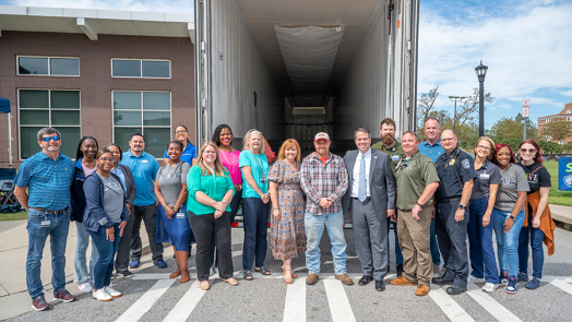 A group of people stand in front of an empty trailer.