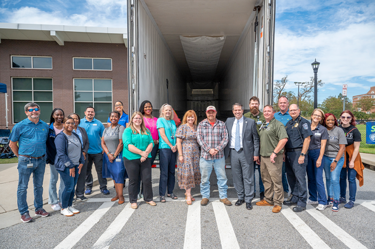 A group of people stand in front of an empty trailer.