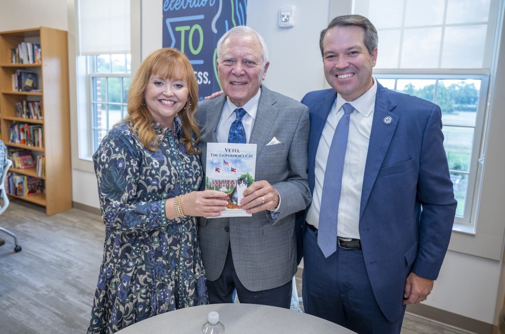 Three people standing holding a book.