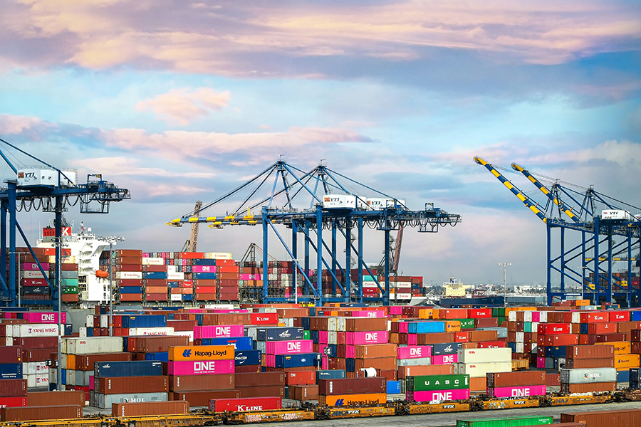 Multiple shipping containers are lined up and stacked high on top of each other.