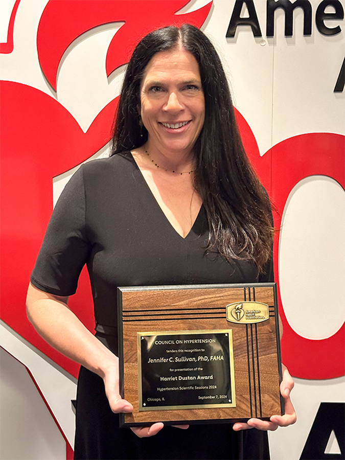 A woman holds a plaque for an award.