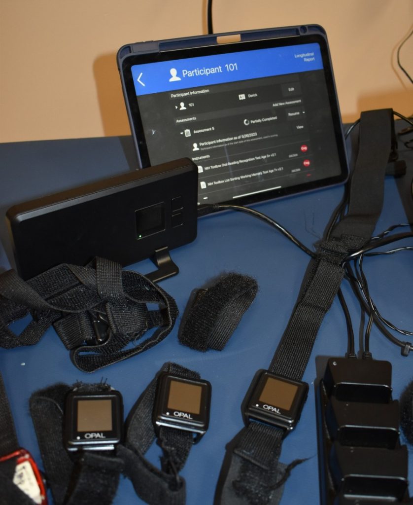 Various sensors lay on a table with a battery pack and tablet.