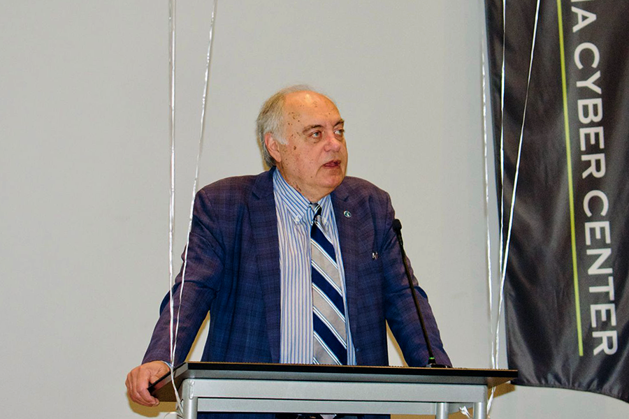 A man stands at a podium and delivers a lecture to a large group of people in a large auditorium.