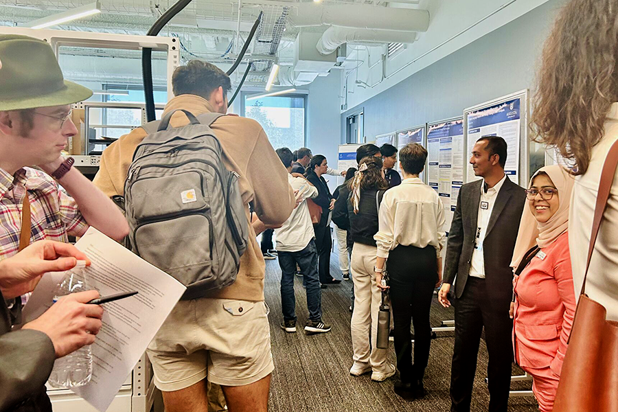 A large group of people look at scientific posters in a room.