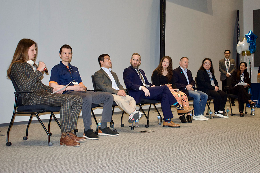 A group of people sit in chairs at the front of a large auditorium and serve as an expert panel.