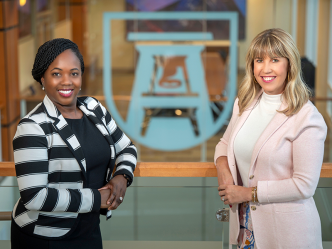 Two women stand next to each other in a large atrium.