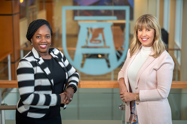 Two women stand next to each other in a large atrium.