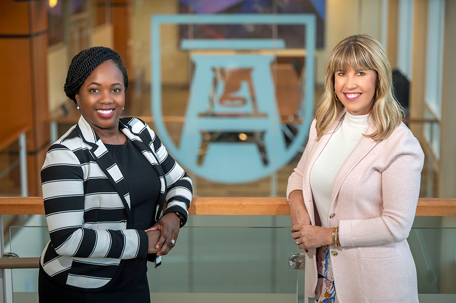 Two women stand next to each other in a large atrium.