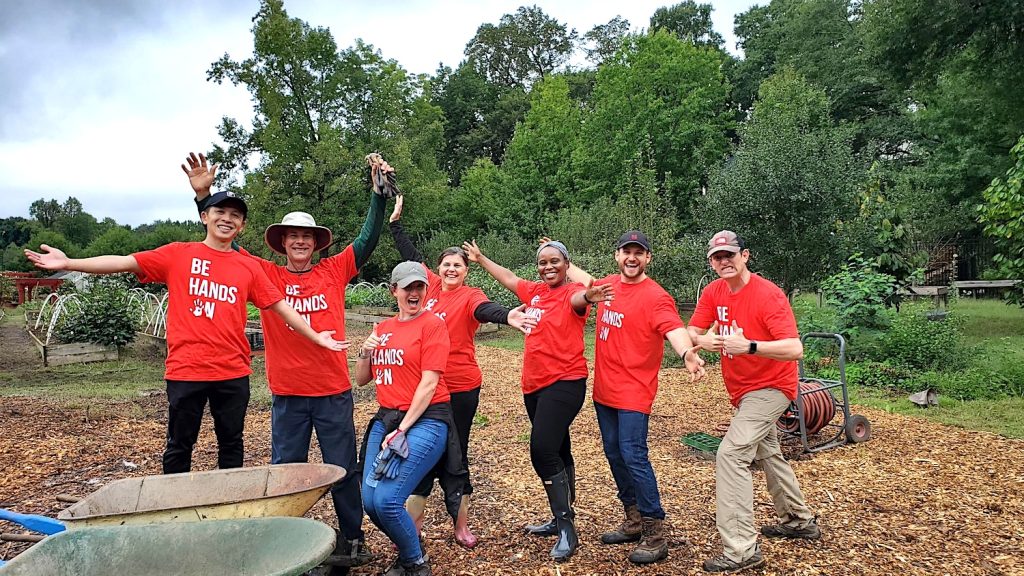 Team of employees posing outside for the camera, all wearing red Be Hands On t-shirts.