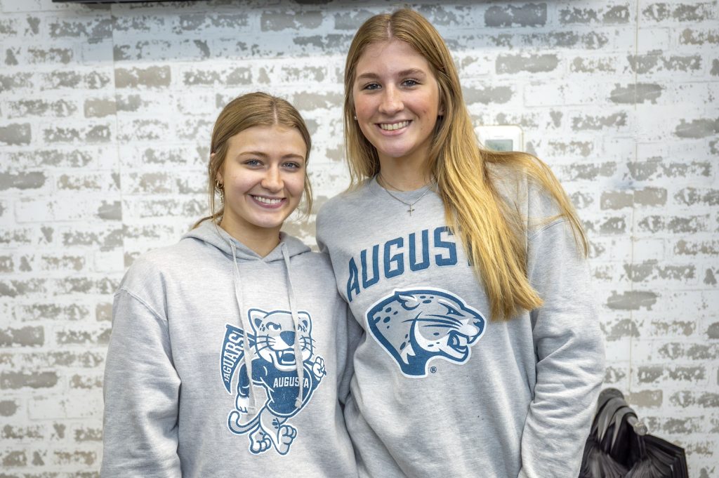 Two college women stand inside in a store.