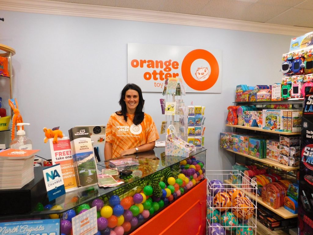 A female small business owner stands behind a check-out counter.