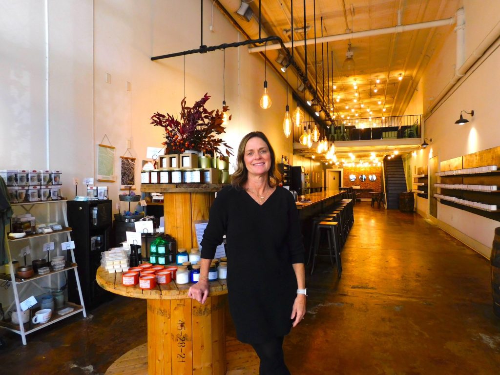 A female small-business owner stands in her candle shop.