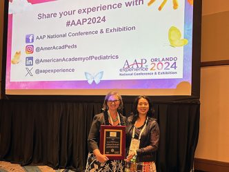 Two women smiling while holding an award