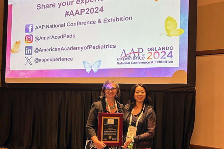 Two women smiling while holding an award