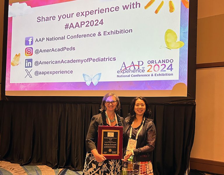 Two women smiling while holding an award