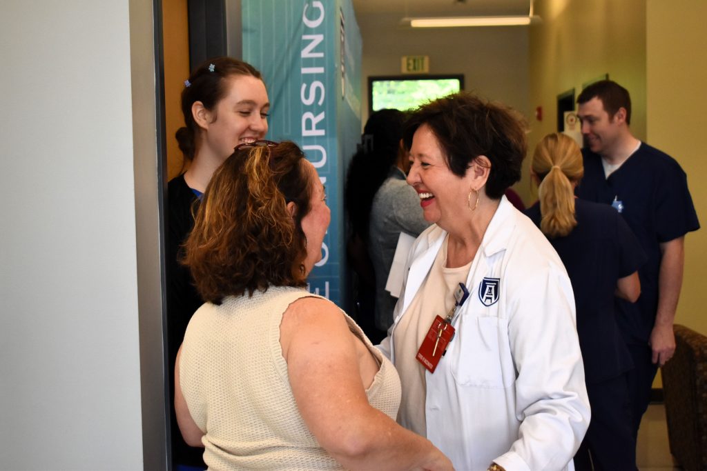 Two women greet each other inside a hallway.