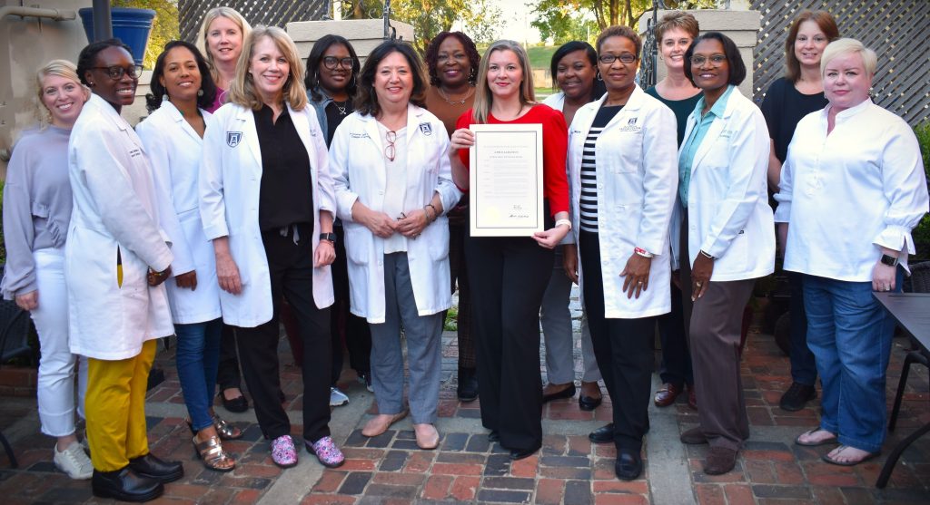 A large group of women gather around one holding a plaque.