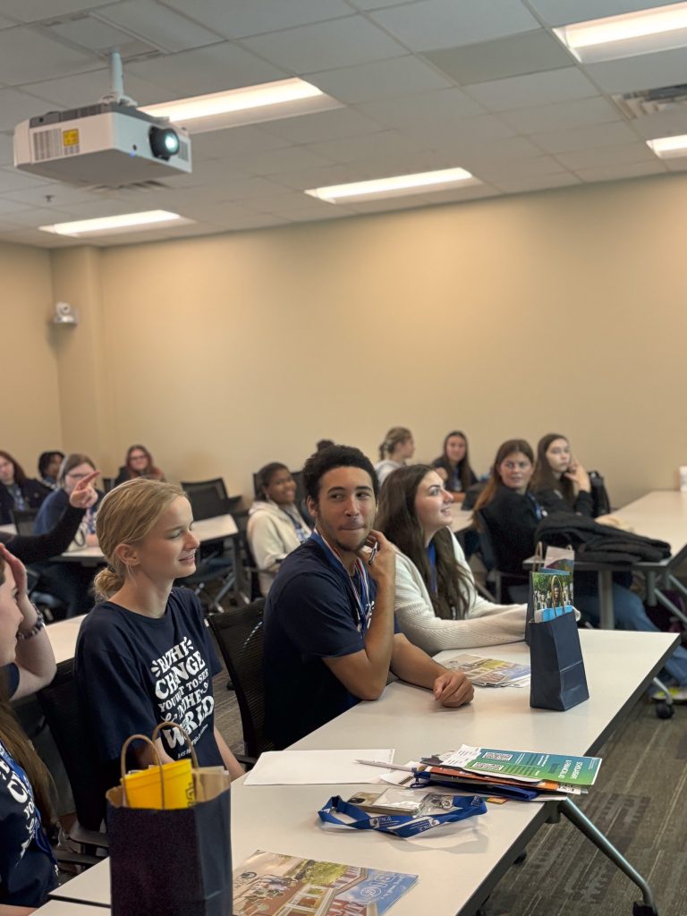 High school students sit in a large classroom during a workshop.