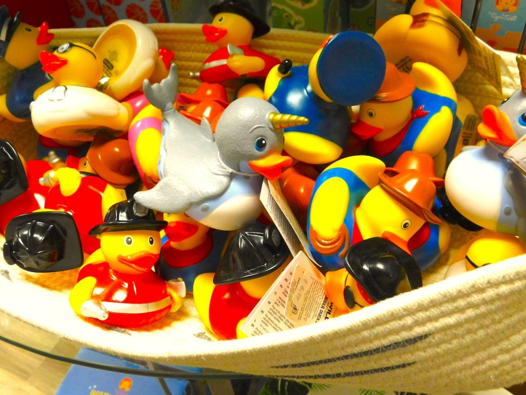 A basket filled with lots of rubber ducks, including some that are dressed like police officers, farmers, fire fighters, doctors and more.