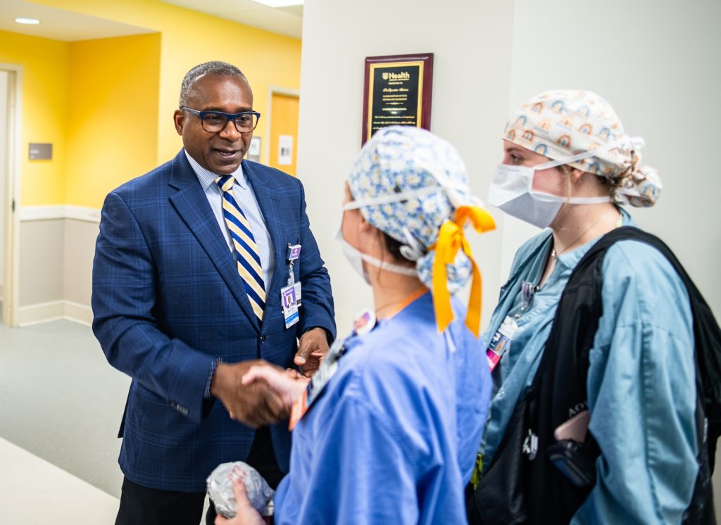 Man shaking hands of medical professionals inside a hospital.