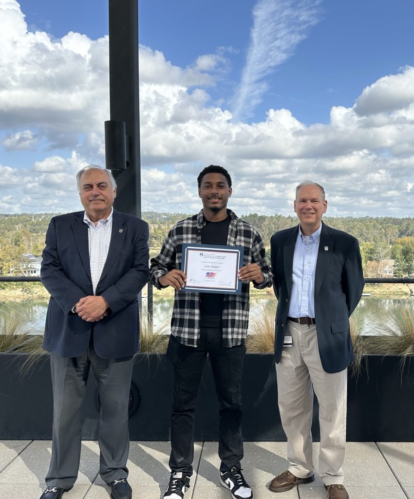 A male college student stand with two college professors during a special ceremony.