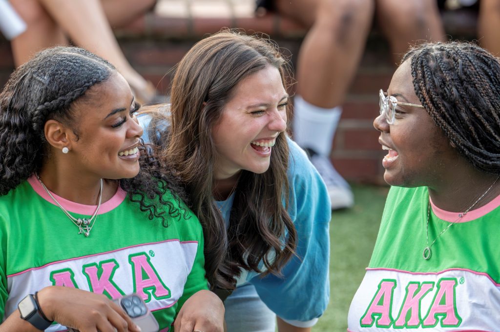 Three women are smiling at each other.