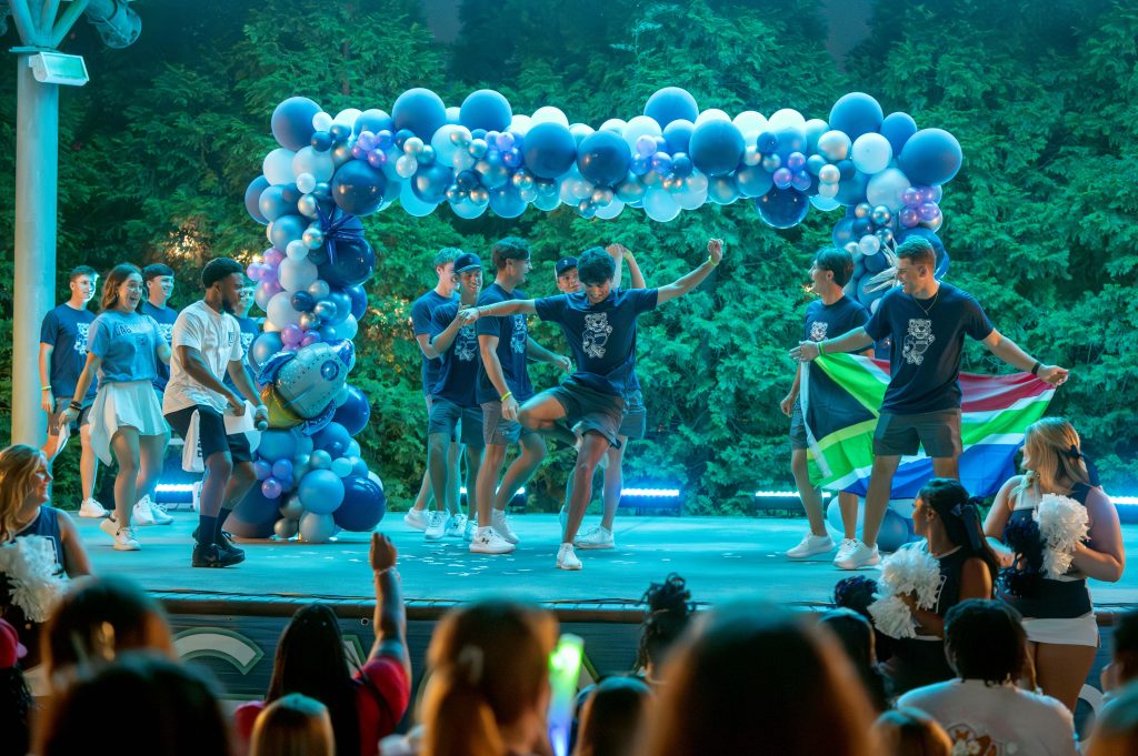 A group of men are dancing on an outdoor stage.