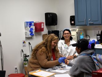 Volunteers perform blood work on a woman in a clinic.