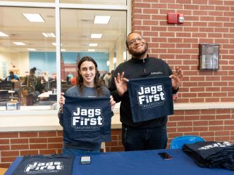 A man and woman hold up shirts that read Jags First.