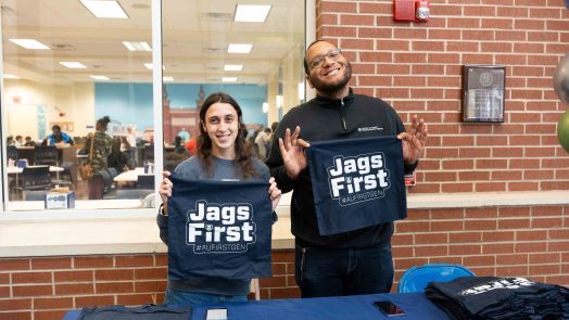 A man and woman hold up shirts that read Jags First.